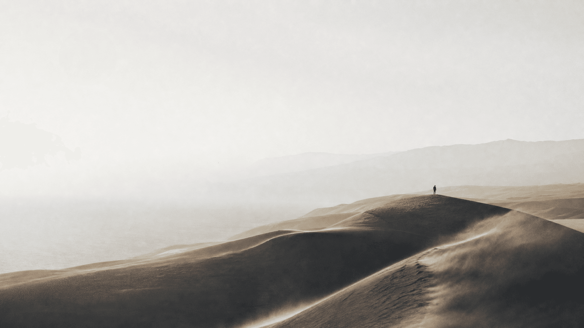 A small anonymous founder figure following a route across a monumental dune.